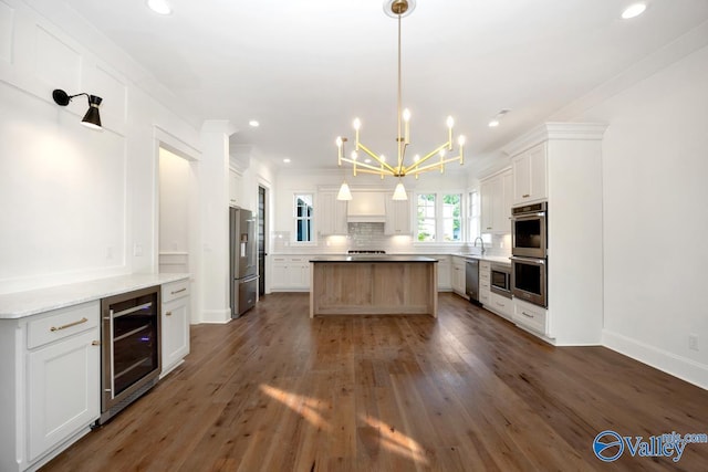 kitchen with beverage cooler, a notable chandelier, dark wood-type flooring, appliances with stainless steel finishes, and a kitchen island