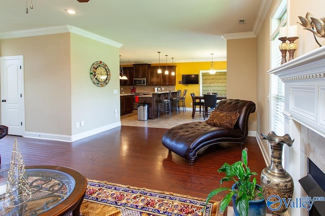 living room with a fireplace, crown molding, and hardwood / wood-style floors