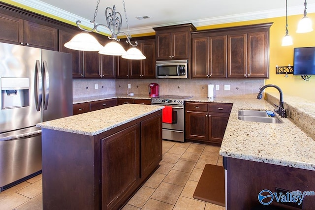 kitchen featuring appliances with stainless steel finishes, light stone countertops, decorative light fixtures, and sink