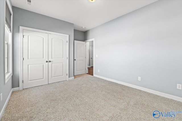 unfurnished bedroom with light carpet and a closet