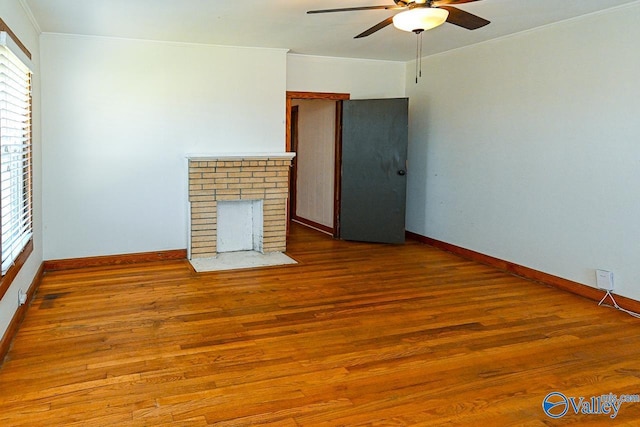 unfurnished living room with hardwood / wood-style floors, ceiling fan, crown molding, and a fireplace