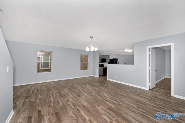 unfurnished living room featuring dark wood-type flooring and an inviting chandelier