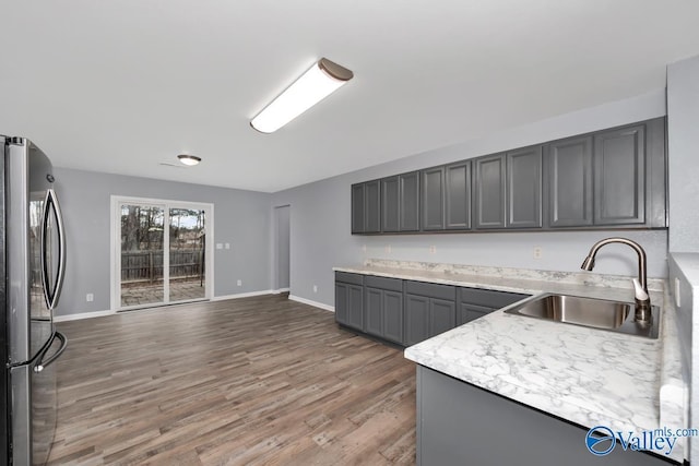 kitchen featuring gray cabinetry, dark hardwood / wood-style flooring, sink, and stainless steel refrigerator