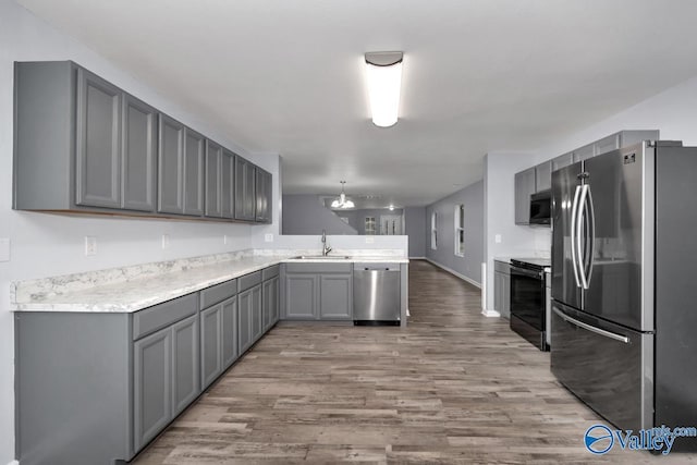 kitchen with stainless steel appliances, an inviting chandelier, light hardwood / wood-style floors, sink, and gray cabinetry