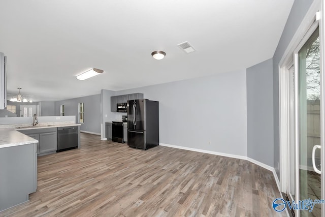 kitchen featuring light hardwood / wood-style floors, gray cabinetry, fridge, dishwasher, and sink