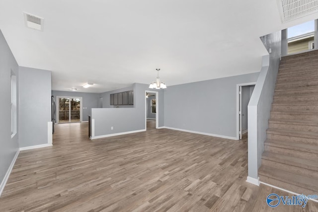 unfurnished living room with an inviting chandelier and light hardwood / wood-style flooring