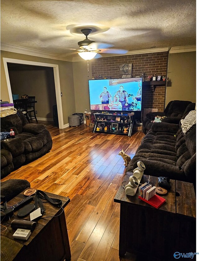 living area featuring wood-type flooring, a textured ceiling, a ceiling fan, and ornamental molding