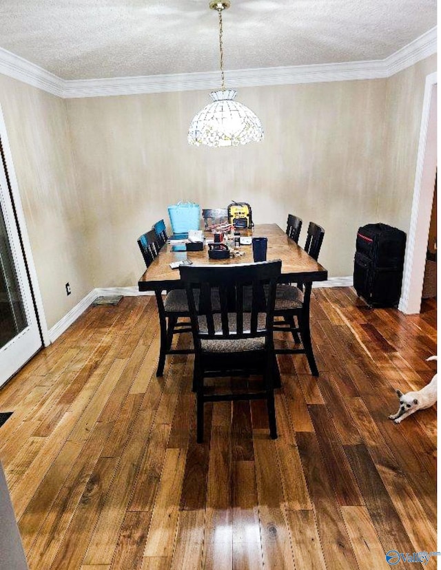 dining area featuring wood-type flooring, a textured ceiling, crown molding, and a notable chandelier