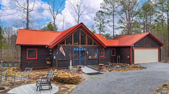 rustic home featuring metal roof, a garage, and driveway