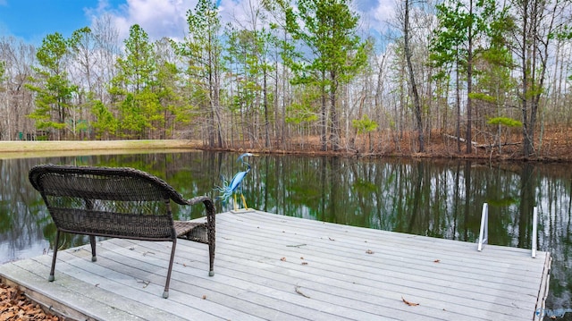 view of dock featuring a wooded view and a water view