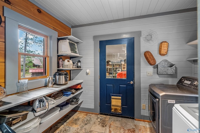 laundry area featuring laundry area, stone finish floor, wooden walls, and wooden ceiling