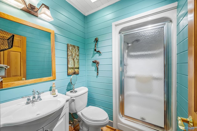 full bathroom featuring wooden walls, toilet, a stall shower, and vanity