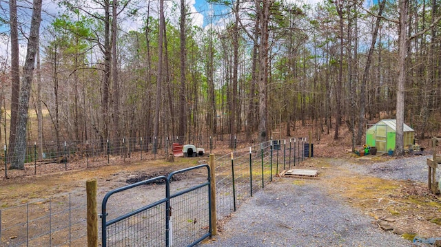 view of road with a gated entry, a wooded view, and a gate