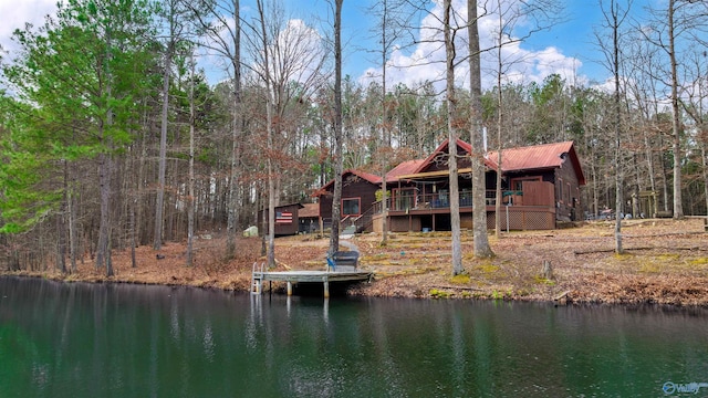 rear view of house with a deck with water view, a forest view, and metal roof