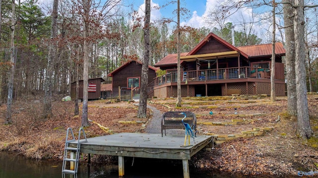 rear view of property featuring a storage unit, a deck with water view, an outdoor structure, and metal roof