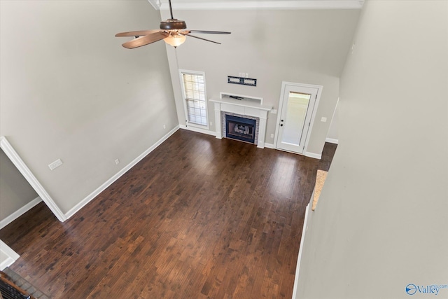 17259 Obsidian Cir, Athens, AL 35613 - unfurnished living room with ceiling fan, a fireplace, baseboards, dark wood-style flooring, and a high ceiling