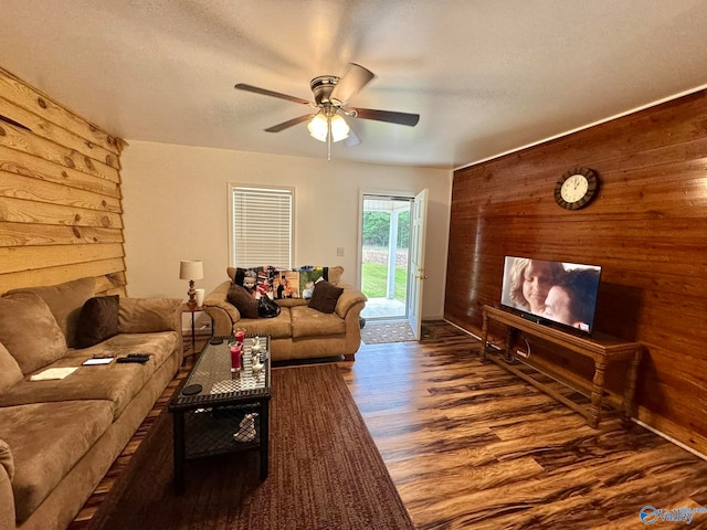 living room featuring a fireplace, a textured ceiling, wood walls, ceiling fan, and dark hardwood / wood-style floors