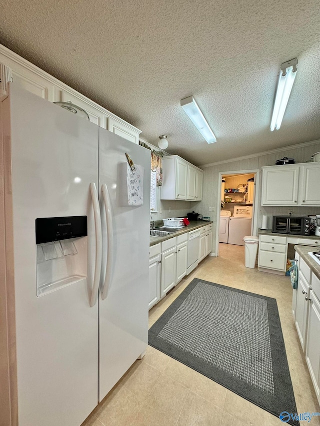 kitchen with white appliances, independent washer and dryer, white cabinets, and a textured ceiling