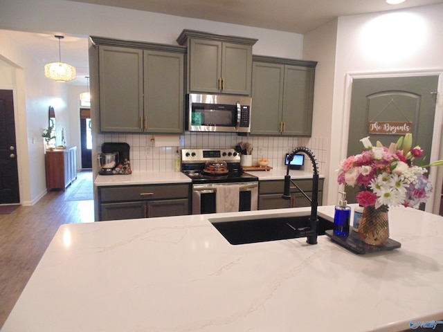110 Oak Path Ln, Harvest, AL 35749 - kitchen with appliances with stainless steel finishes, decorative backsplash, wood finished floors, a sink, and light stone countertops