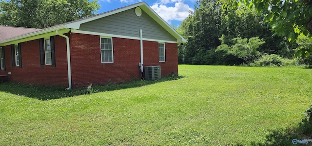 view of property exterior featuring central air condition unit, a lawn, and brick siding