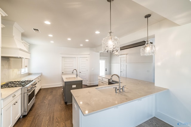 kitchen featuring an island with sink, dark wood-style floors, custom range hood, and a sink