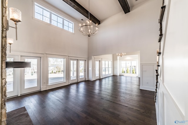 unfurnished living room with a chandelier, beam ceiling, and dark wood-type flooring