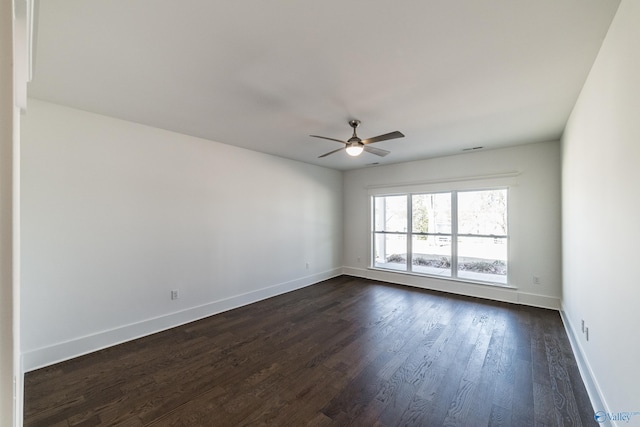 empty room featuring dark wood-style floors, a ceiling fan, and baseboards