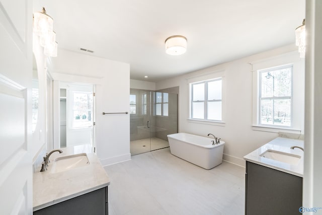 full bath with a shower stall, two vanities, and a sink