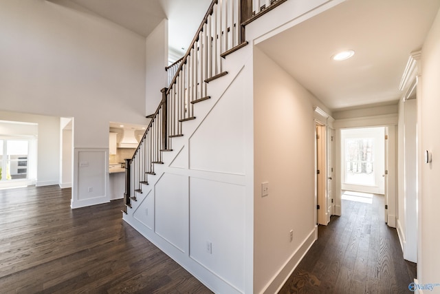 stairs with a towering ceiling, baseboards, and wood finished floors