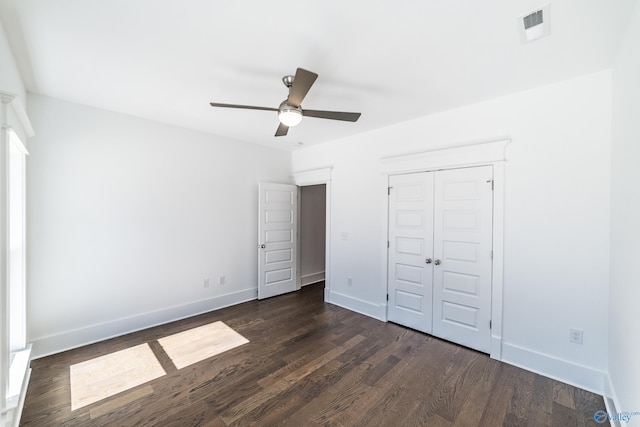 unfurnished bedroom featuring dark wood-style floors, a closet, visible vents, and baseboards