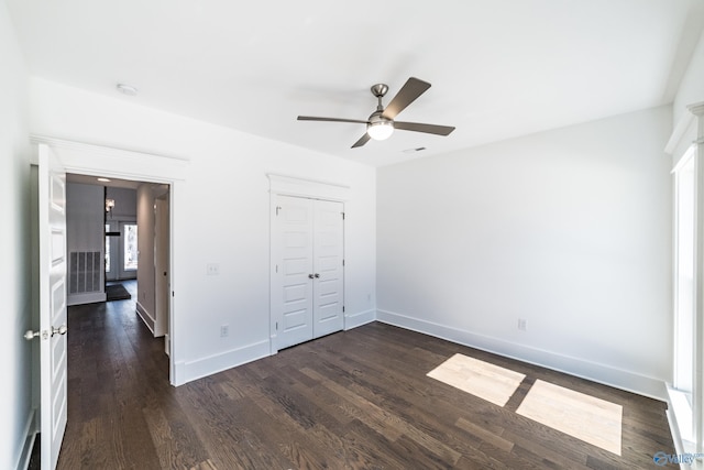 unfurnished bedroom featuring a closet, visible vents, dark wood-type flooring, ceiling fan, and baseboards