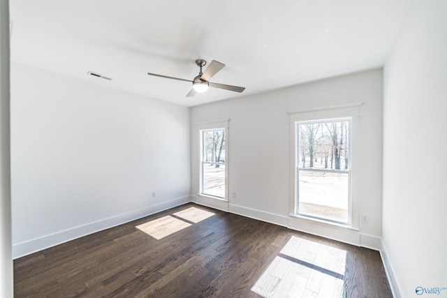 spare room with ceiling fan, dark wood-type flooring, visible vents, and baseboards