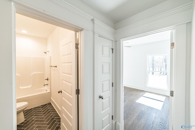 full bath with tub / shower combination, wood finished floors, toilet, and baseboards