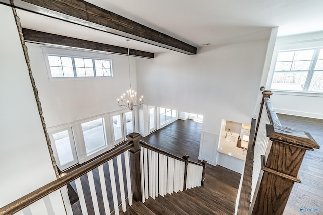 staircase featuring beam ceiling, baseboards, an inviting chandelier, and wood finished floors