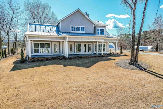 view of front of house with a standing seam roof, a front lawn, metal roof, and board and batten siding