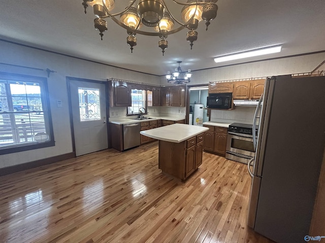 kitchen with a kitchen island, stainless steel appliances, light countertops, a chandelier, and a sink