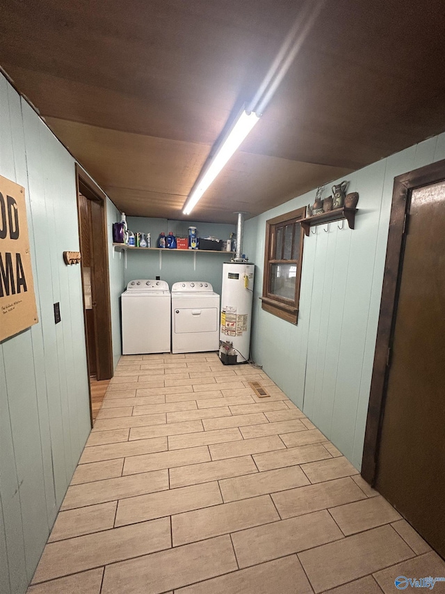 laundry area featuring laundry area, washer and dryer, light wood-type flooring, wood walls, and water heater