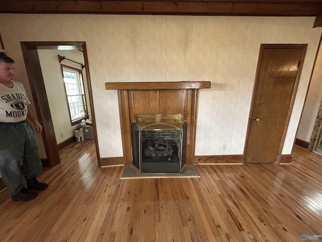 unfurnished living room featuring wood-type flooring, a fireplace, and baseboards