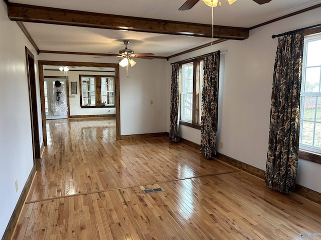 spare room featuring baseboards, a ceiling fan, crown molding, light wood-type flooring, and beam ceiling