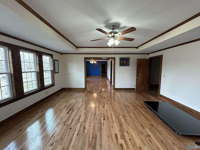 empty room with a textured ceiling, wood-type flooring, and a raised ceiling