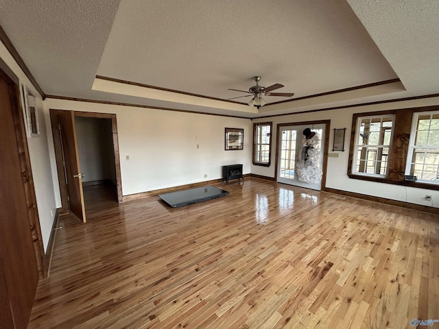 unfurnished living room with a tray ceiling, a textured ceiling, and wood finished floors