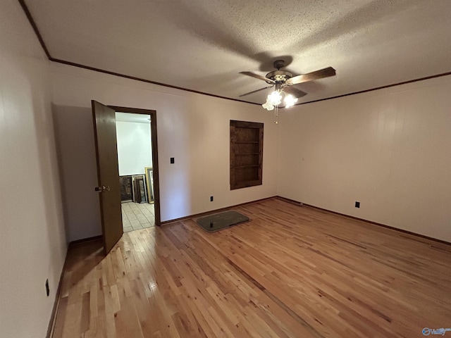 empty room with light wood-type flooring, ceiling fan, ornamental molding, and a textured ceiling