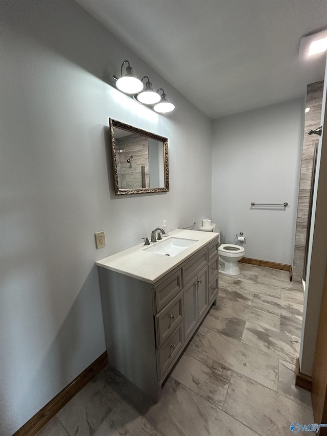 full bathroom featuring toilet, baseboards, a shower, and vanity