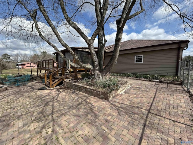 rear view of house featuring metal roof, a patio, and a deck