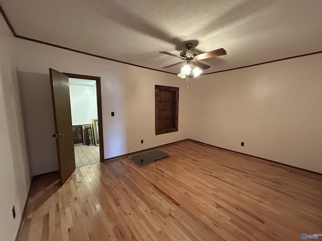 spare room with a textured ceiling, ornamental molding, and light wood-style floors