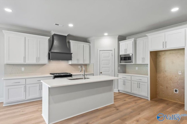 kitchen with appliances with stainless steel finishes, custom exhaust hood, white cabinetry, and light hardwood / wood-style flooring