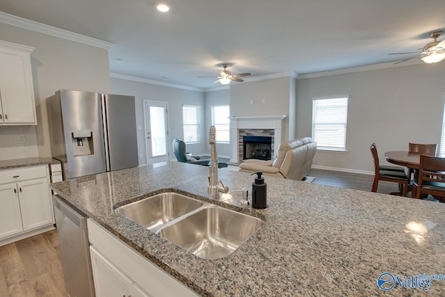 kitchen featuring appliances with stainless steel finishes, a fireplace, a sink, and a ceiling fan