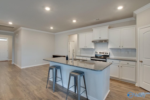 kitchen featuring a breakfast bar area, visible vents, a sink, stainless steel range with electric stovetop, and under cabinet range hood