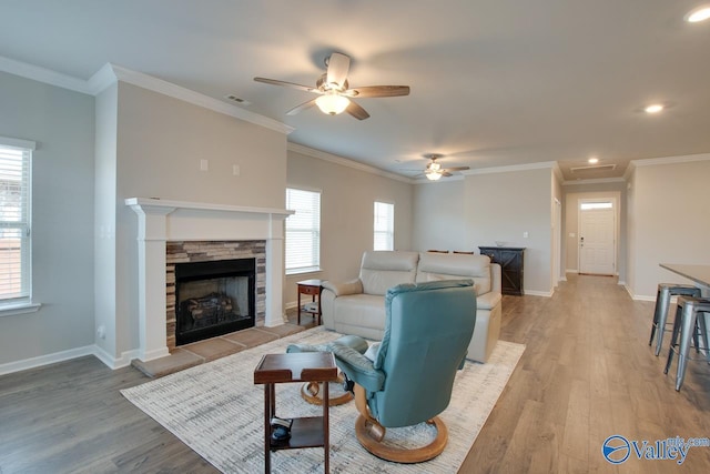 living area featuring light wood finished floors, plenty of natural light, baseboards, and a tiled fireplace