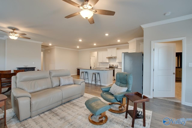 living room featuring ornamental molding, recessed lighting, baseboards, and wood finished floors